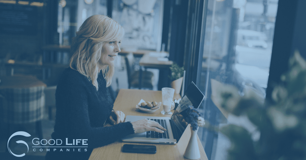 A woman sits at a window seat at a cafe with her laptop